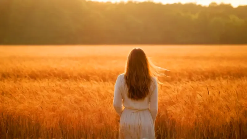 Mujer en un campo dorado al atardecer