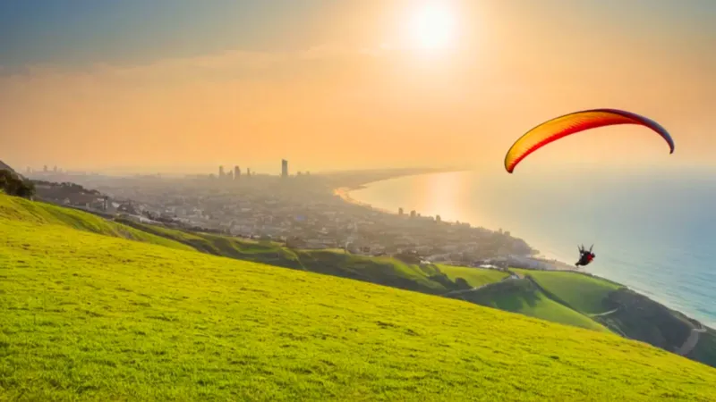 Un parapentista vuela sobre la ciudad costera