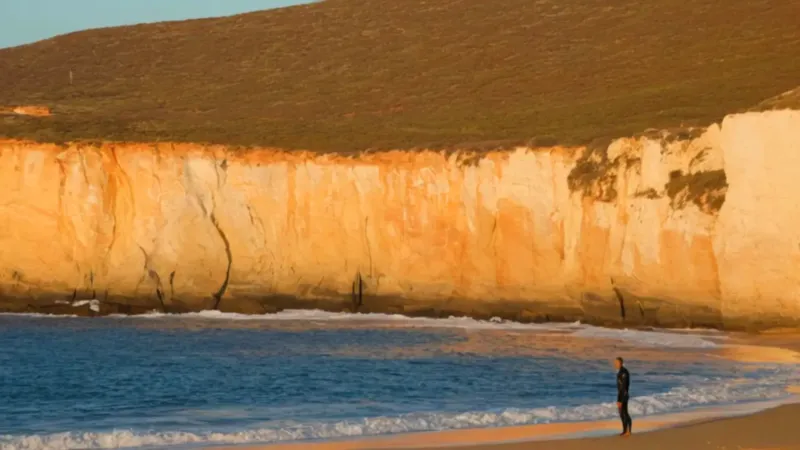 Surfista contempla el mar desde el acantilado