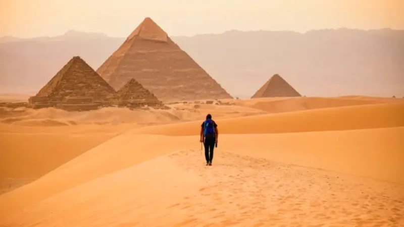 Una figura contempla las pirámides al atardecer