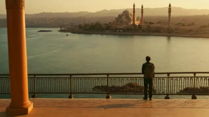 Viajero contempla la ciudad lejana al atardecer