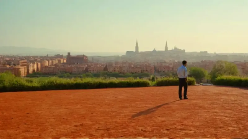 Una figura observa la ciudad al atardecer