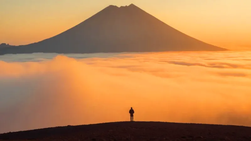 Un hombre observa el amanecer volcánico